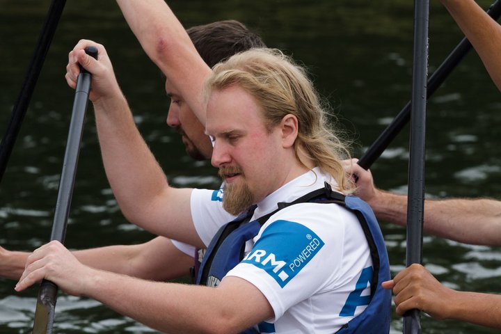 Me in a dragon boat, holding a paddle, wearing a t-shirt that says 'ARM Powered' on the sleeve...